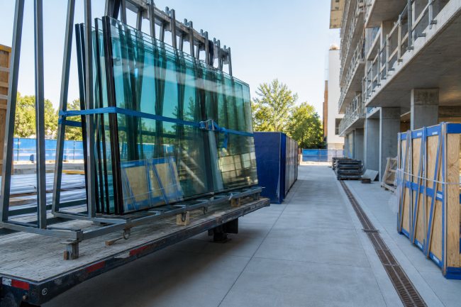 Commercial glass delivery arriving at a prepared construction jobsite staging area.