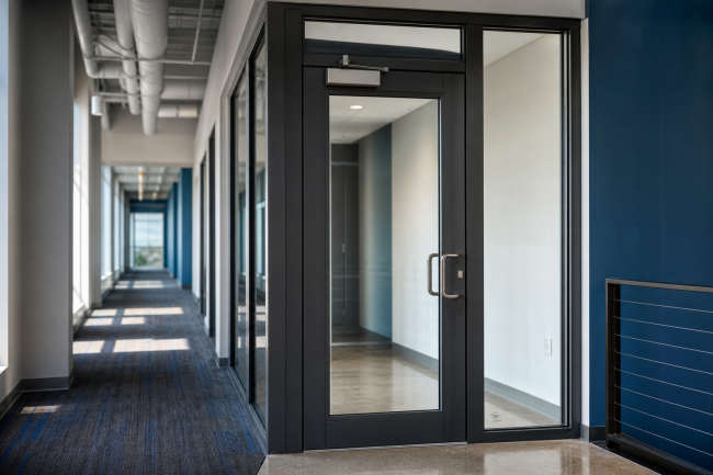 Fire-Protective Vs Fire-Resistive Glass: fire-rated glass door and sidelite in an aluminum frame at a commercial interior opening